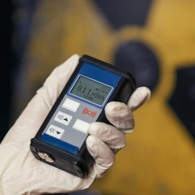 Misuratore della radioattività naturale e artificiale. Dispositivo nero sostenuto da una mano con un guanto bianco.